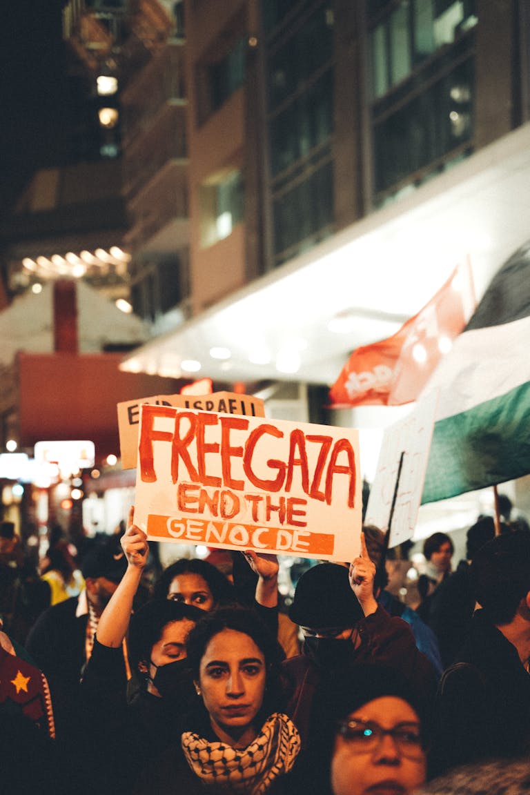 A night protest advocating for Gaza's liberation with a large crowd holding signs.