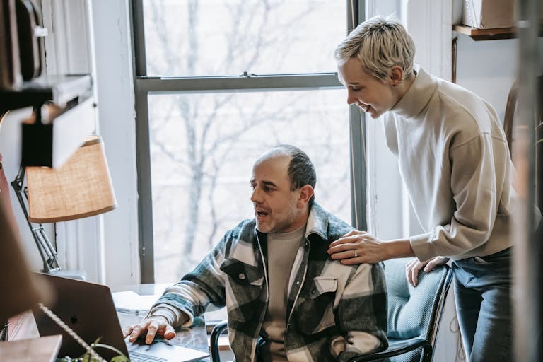 Cheerful colleagues working together on a laptop in a bright workspace.