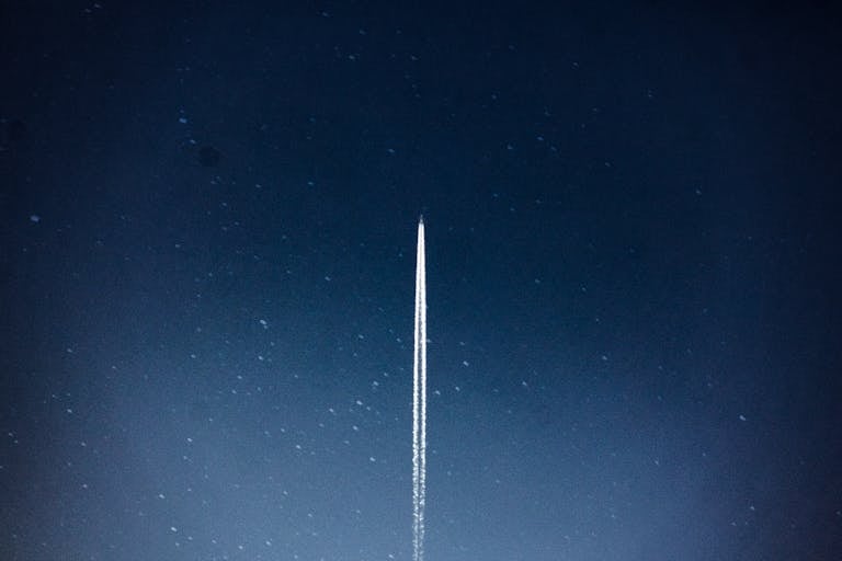 A rocket streaks through a starry night, leaving a trail in outer space.